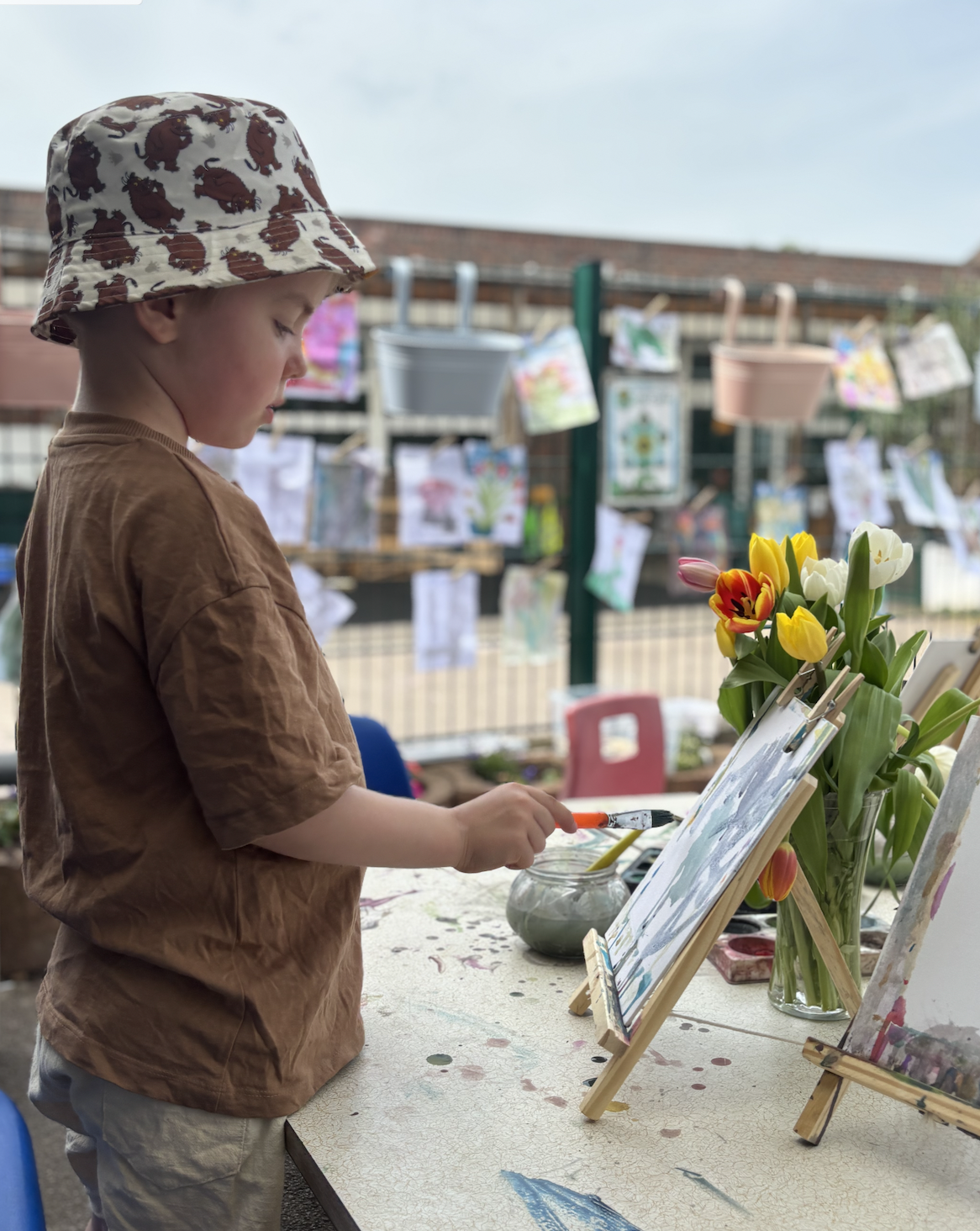 Child painting at an easel outdoors at Little Imaginations